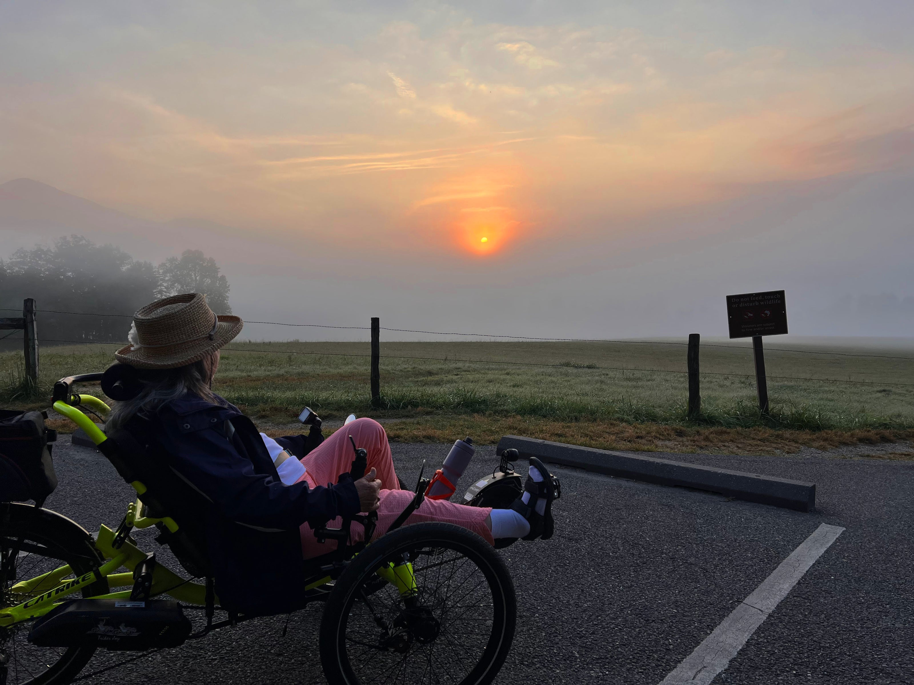A person on a recumbent trike at sunset with a scenic view.
