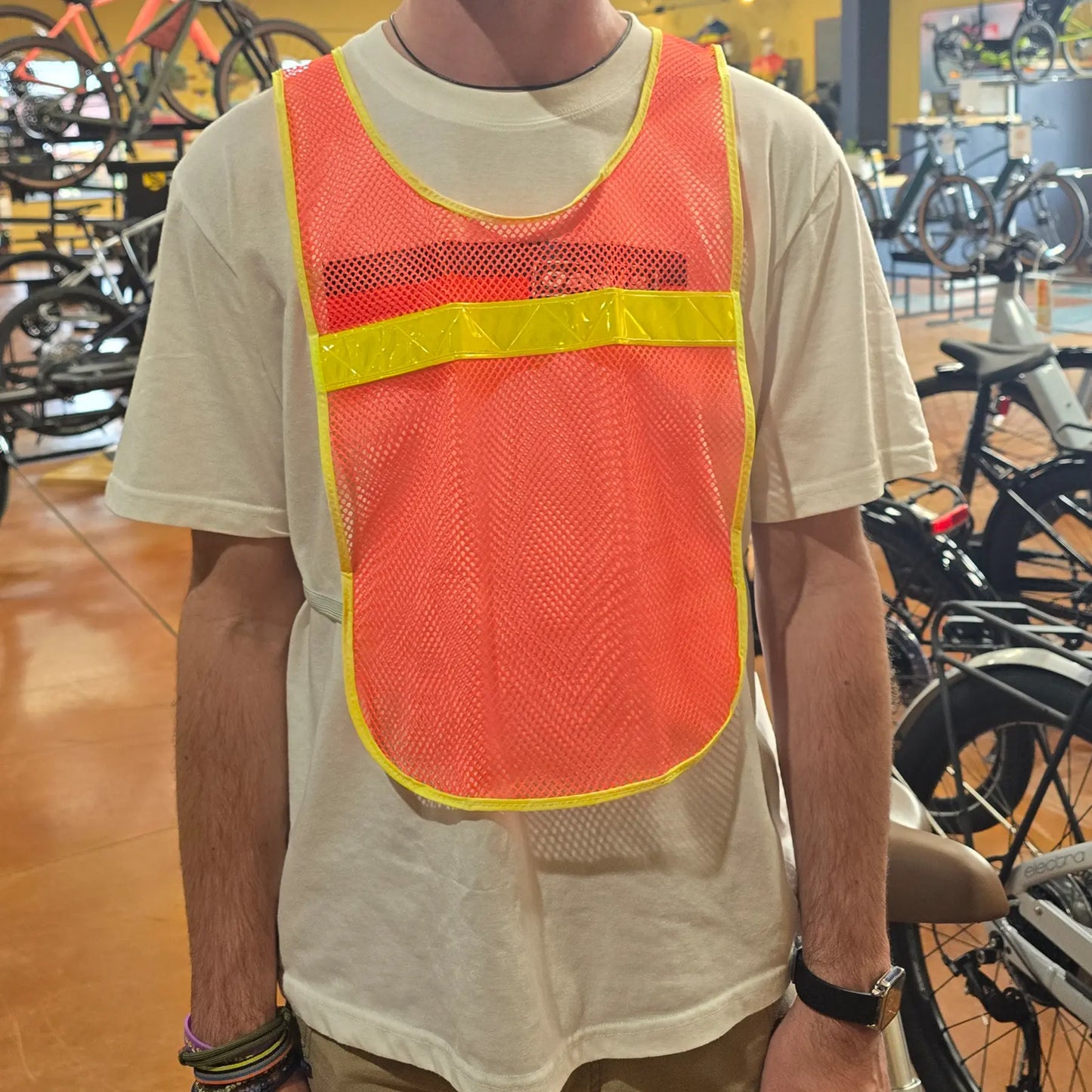 Front view of the Aardvark reflective Vest in orange high-visibility mesh with a bright yellow reflective horizontal stripe and yellow trim, shown on a model.