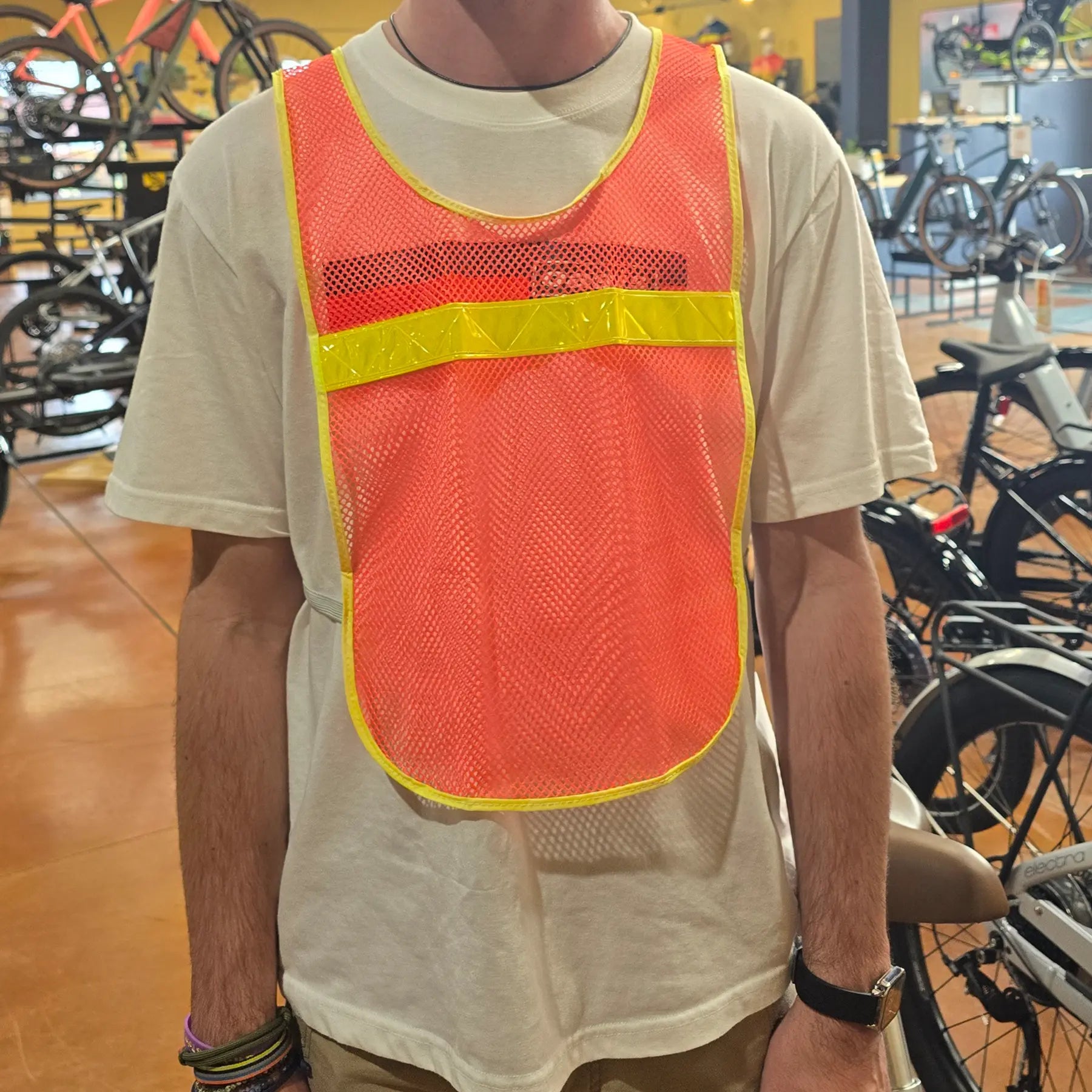 Front view of the Aardvark reflective Vest in orange high-visibility mesh with a bright yellow reflective horizontal stripe and yellow trim, shown on a model.