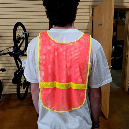 Back view of the Aardvark reflective Vest in orange high-visibility mesh with a bright yellow reflective horizontal stripe and yellow trim, shown on a model.