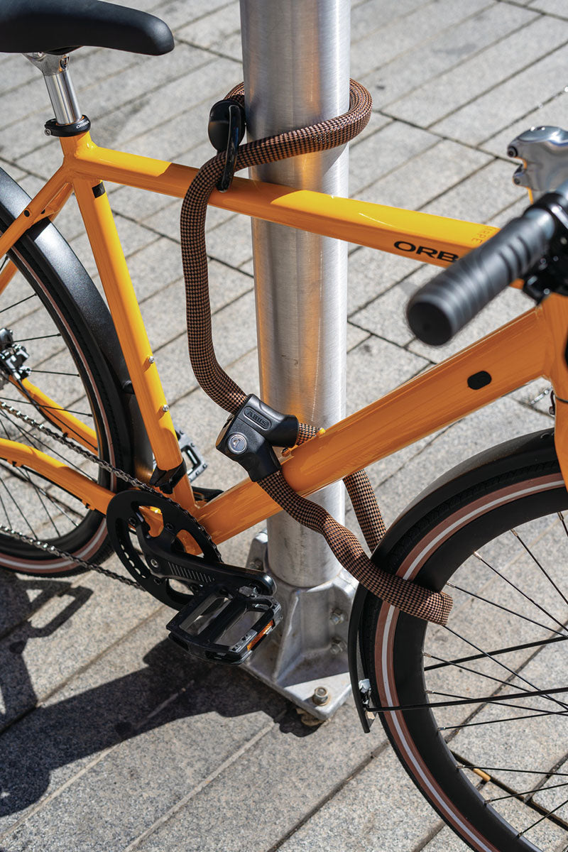 Abus Infinity Loop 1806 brown cable Lock shown securing a bike to a pole.