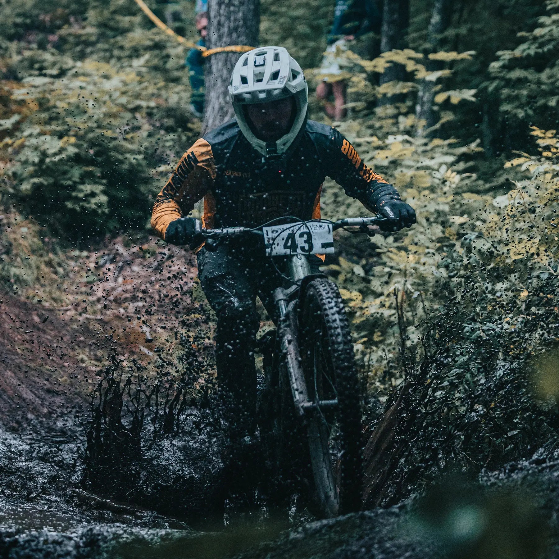 Biker on a mountain bike navigating a muddy trail in a forest.