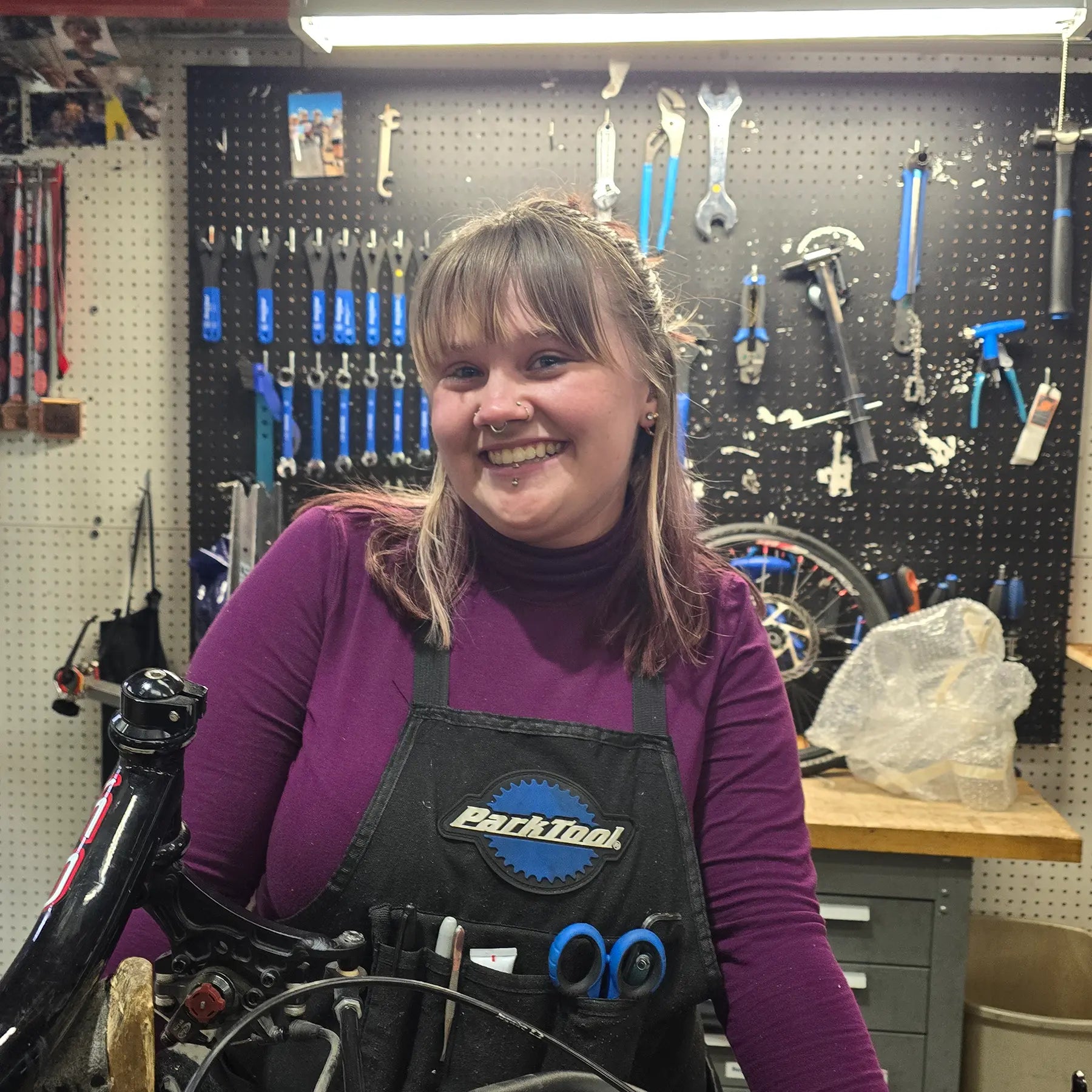 Ava, Mechanic, in front of her work bench and tool board.