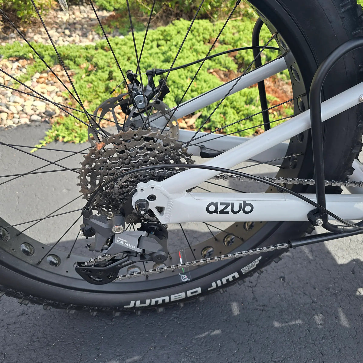 Closeup view of the Jumbo Jim tire, rear wheel, cassette and rear dearilleur on the Azub Demo Fat Bosch Performance CX Dynamic Grey Recumbent Trike in an outdoor setting.