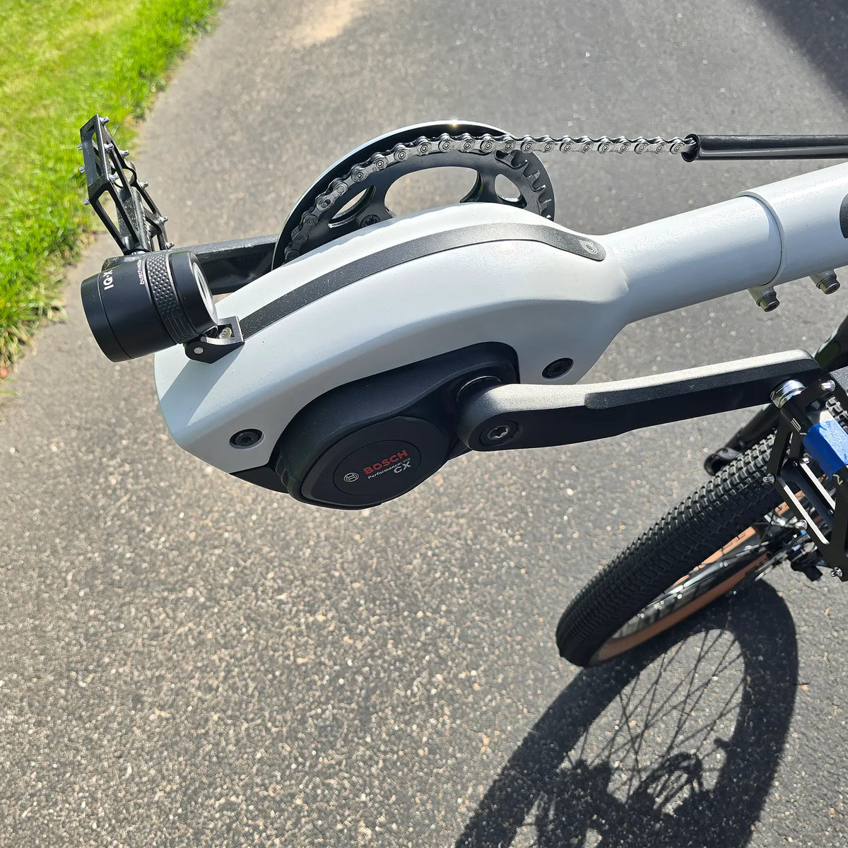 Closeup view of the Bosch motor and headlight on the Azub Demo Six Bosch Performance CX Dynamic Grey Recumbent Bike in an outdoor setting.