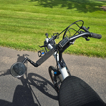Closeup view of the handlebars with mirror and Bosch controller on the Azub Demo Six Bosch Performance CX Dynamic Grey Recumbent Bike in an outdoor setting.