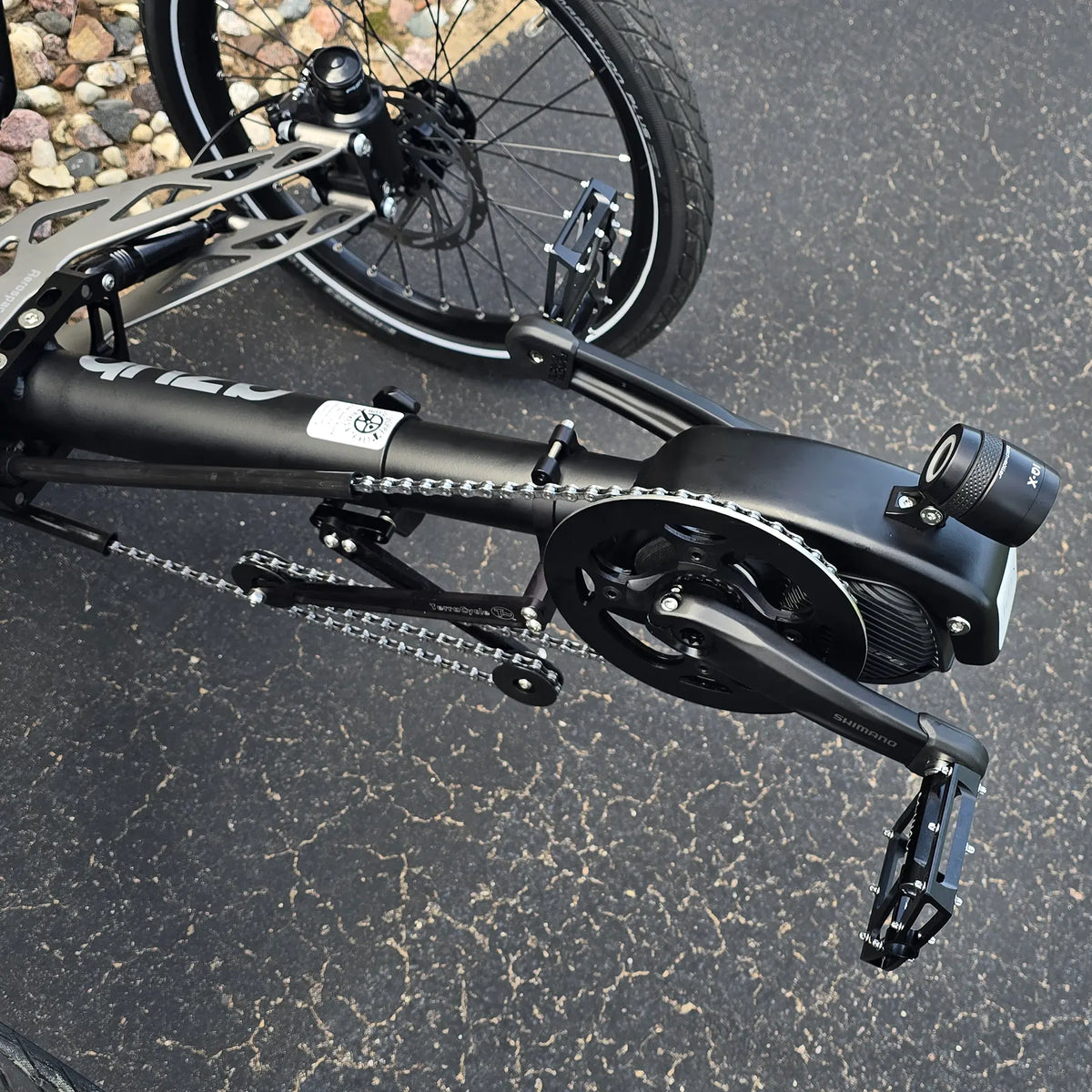 Closeup view of the Shimano motor, headlight and quick adjust on the Azub Demo Ti-Fly 26 Shimano EP6 Deep Black Recumbent Trike in an outdoor setting.