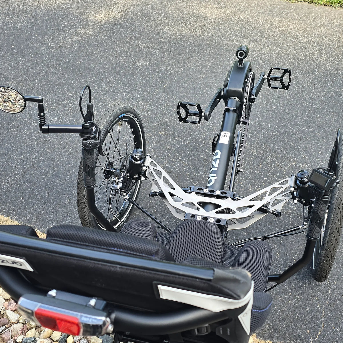 Closeup view of the mirror, front suspension and handlebars with controls on the Azub Demo Ti-Fly 26 Shimano EP6 Deep Black Recumbent Trike in an outdoor setting.