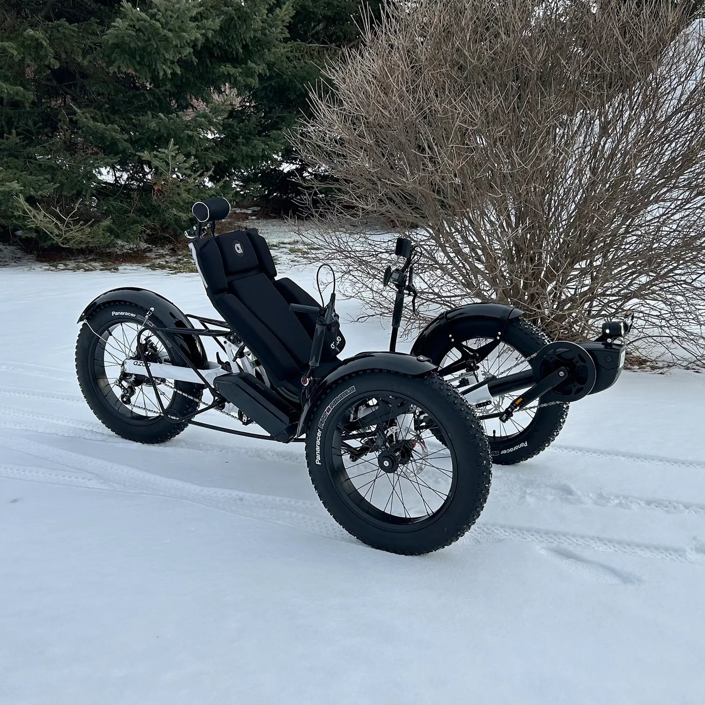 Azub Limited Edition Ti-Fly recumbent trike on a snowy path with trees and bushes in the background.
