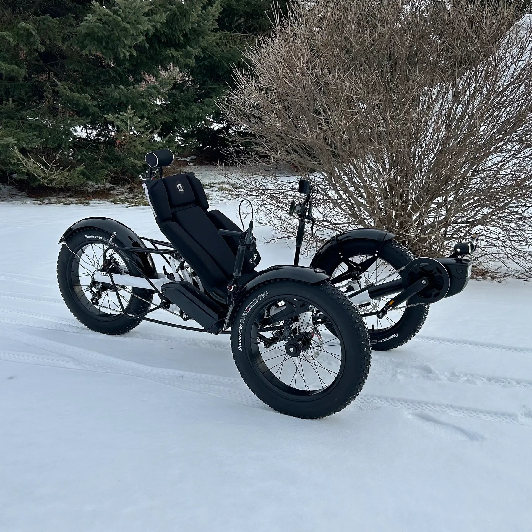 Azub Limited Edition Ti-Fly recumbent trike on a snowy path with trees and bushes in the background.