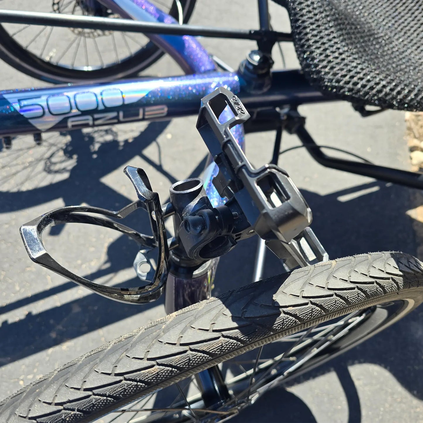 Closeup view of the accessory mount, bottle cage and phone mount on the Azub Used T-Tris 5000 Chameleon Teal Custom Recumbent Trike in an outdoor setting.