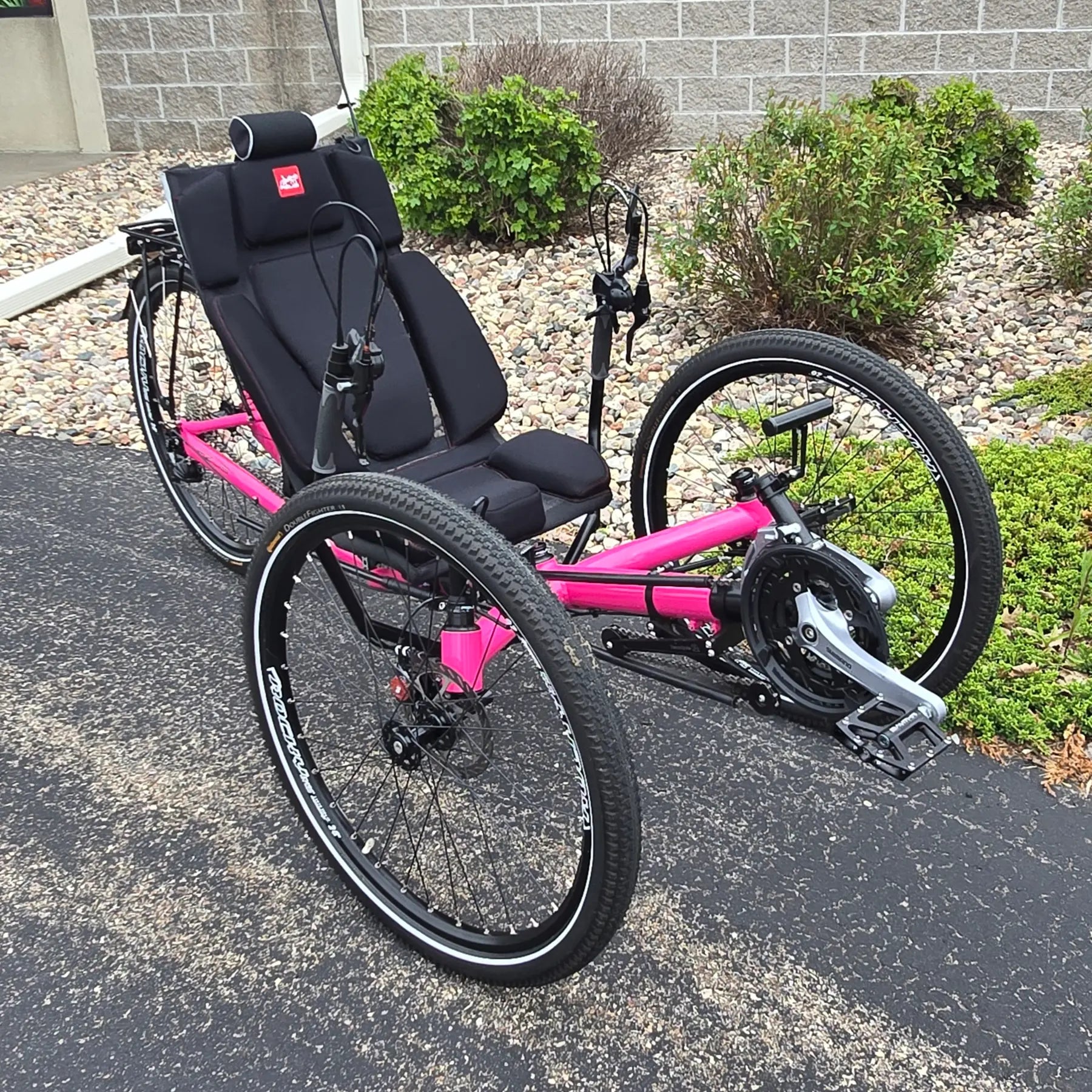 Angled side view of the Azub Used T-Tris AR Neon Pink Recumbent Trike in an outdoor setting.