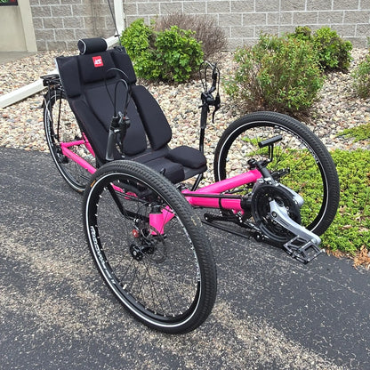 Angled side view of the Azub Used T-Tris AR Neon Pink Recumbent Trike in an outdoor setting.