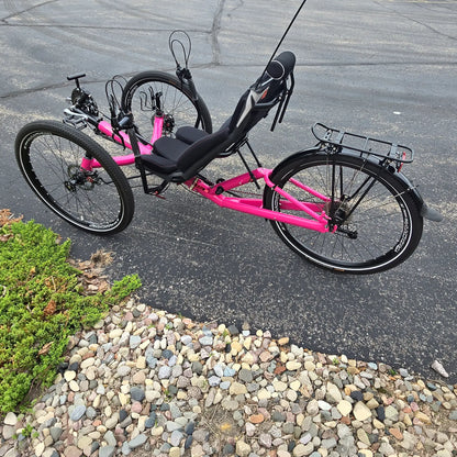 Non-drive side view of the Azub Used T-Tris AR Neon Pink Recumbent Trike in an outdoor setting.