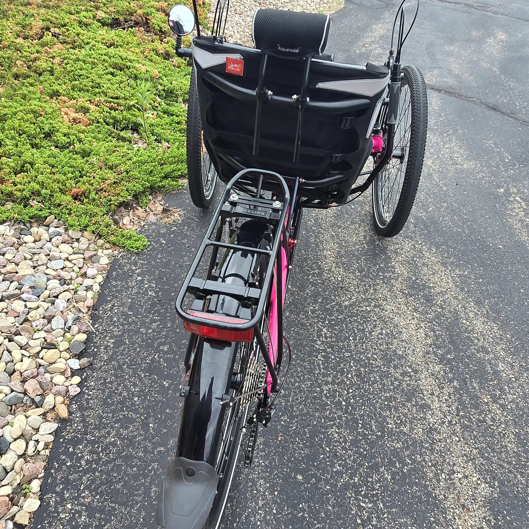 Rear view of the Azub Used T-Tris AR Neon Pink Recumbent Trike in an outdoor setting.
