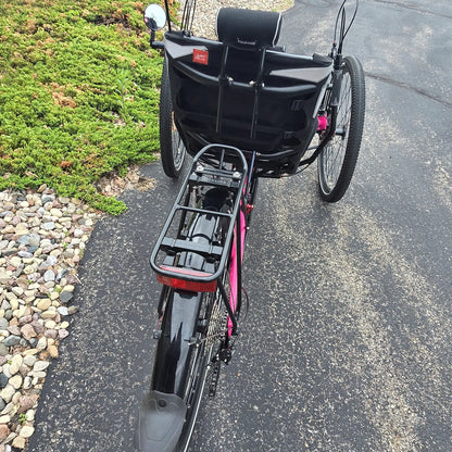 Rear view of the Azub Used T-Tris AR Neon Pink Recumbent Trike in an outdoor setting.