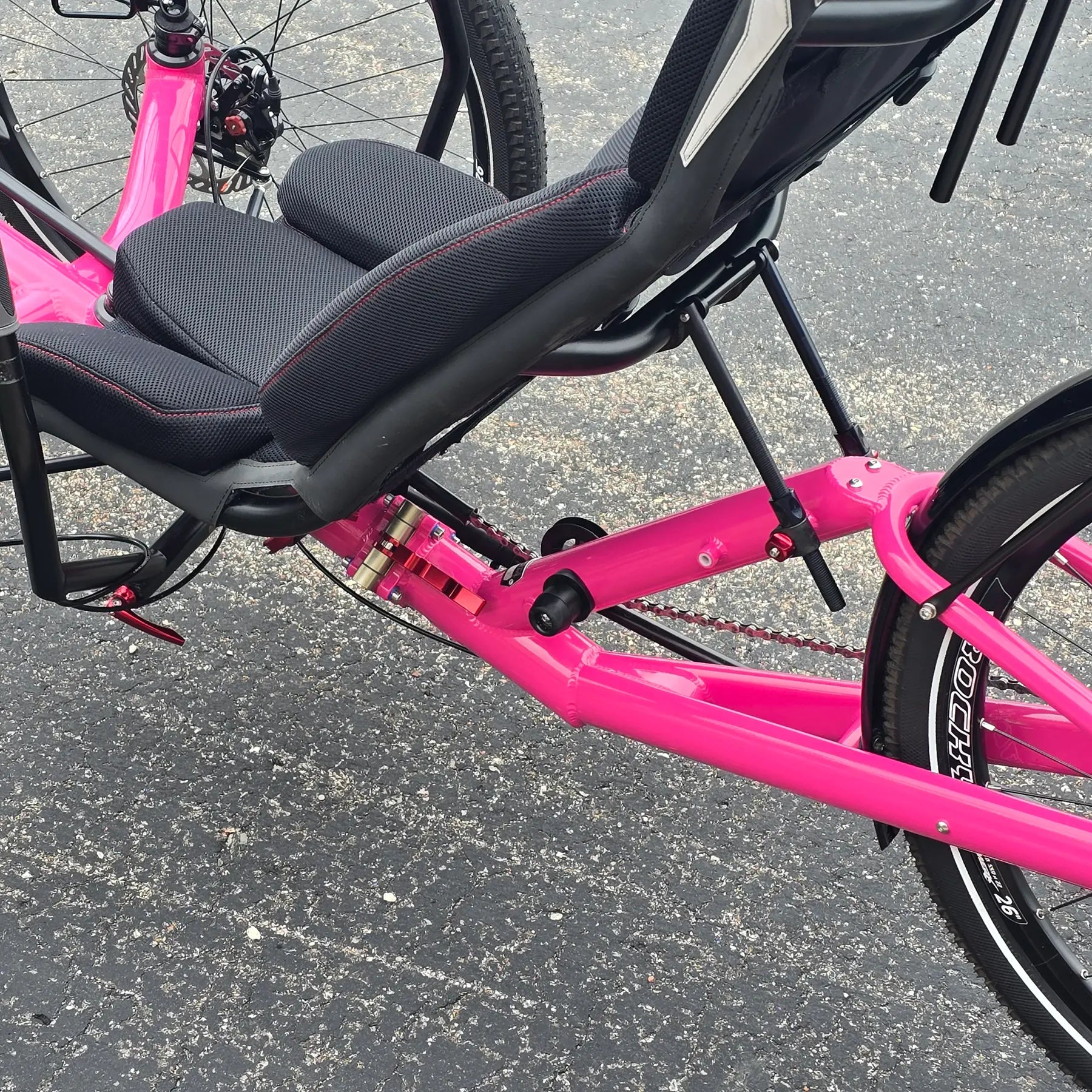 Closeup view of the folding hinge on the Azub Used T-Tris AR Neon Pink Recumbent Trike in an outdoor setting.