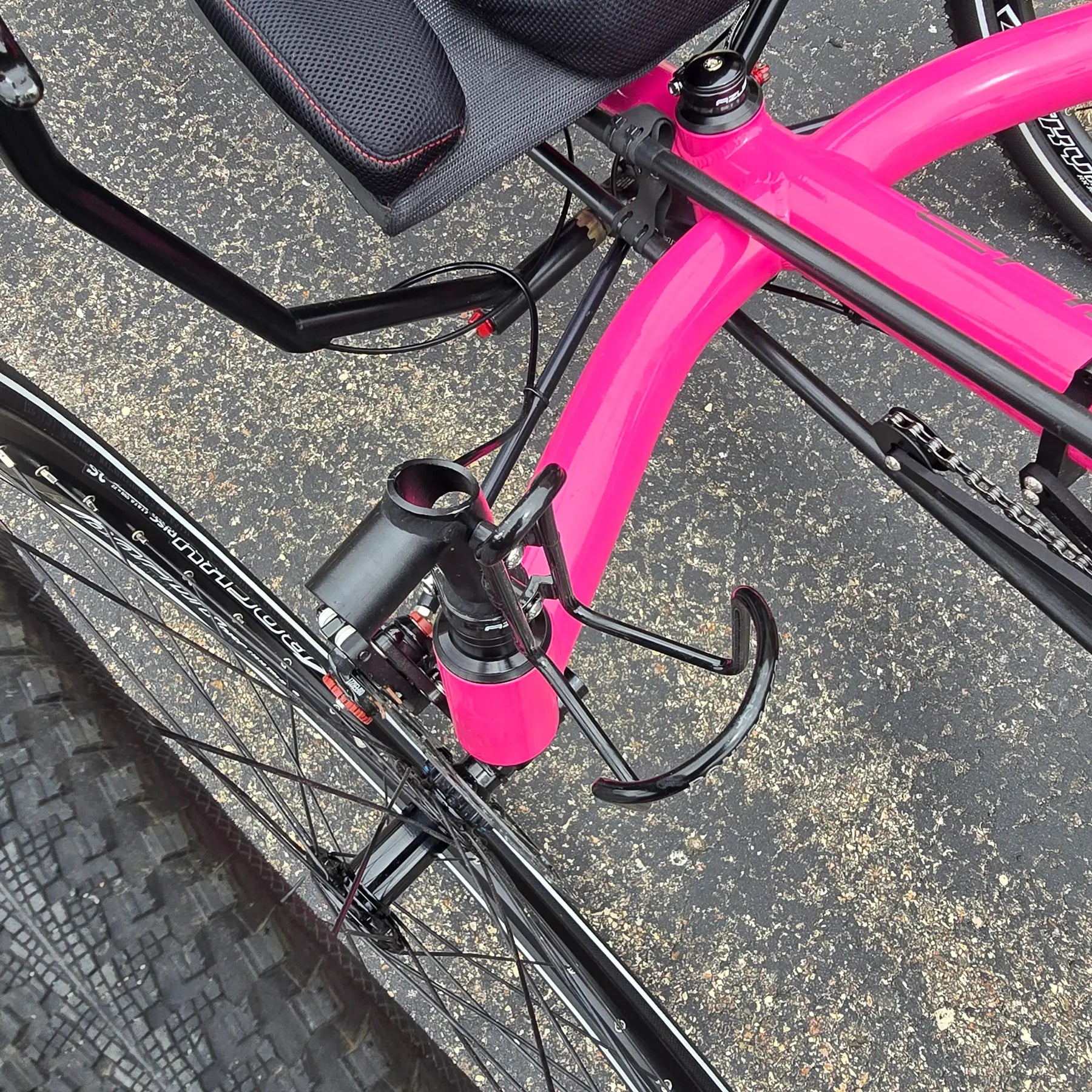 Closeup view of the accessory mount and bottle cage on the Azub Used T-Tris AR Neon Pink Recumbent Trike in an outdoor setting.