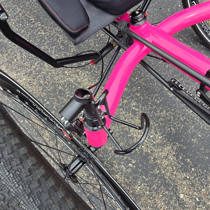 Closeup view of the accessory mount and bottle cage on the Azub Used T-Tris AR Neon Pink Recumbent Trike in an outdoor setting.