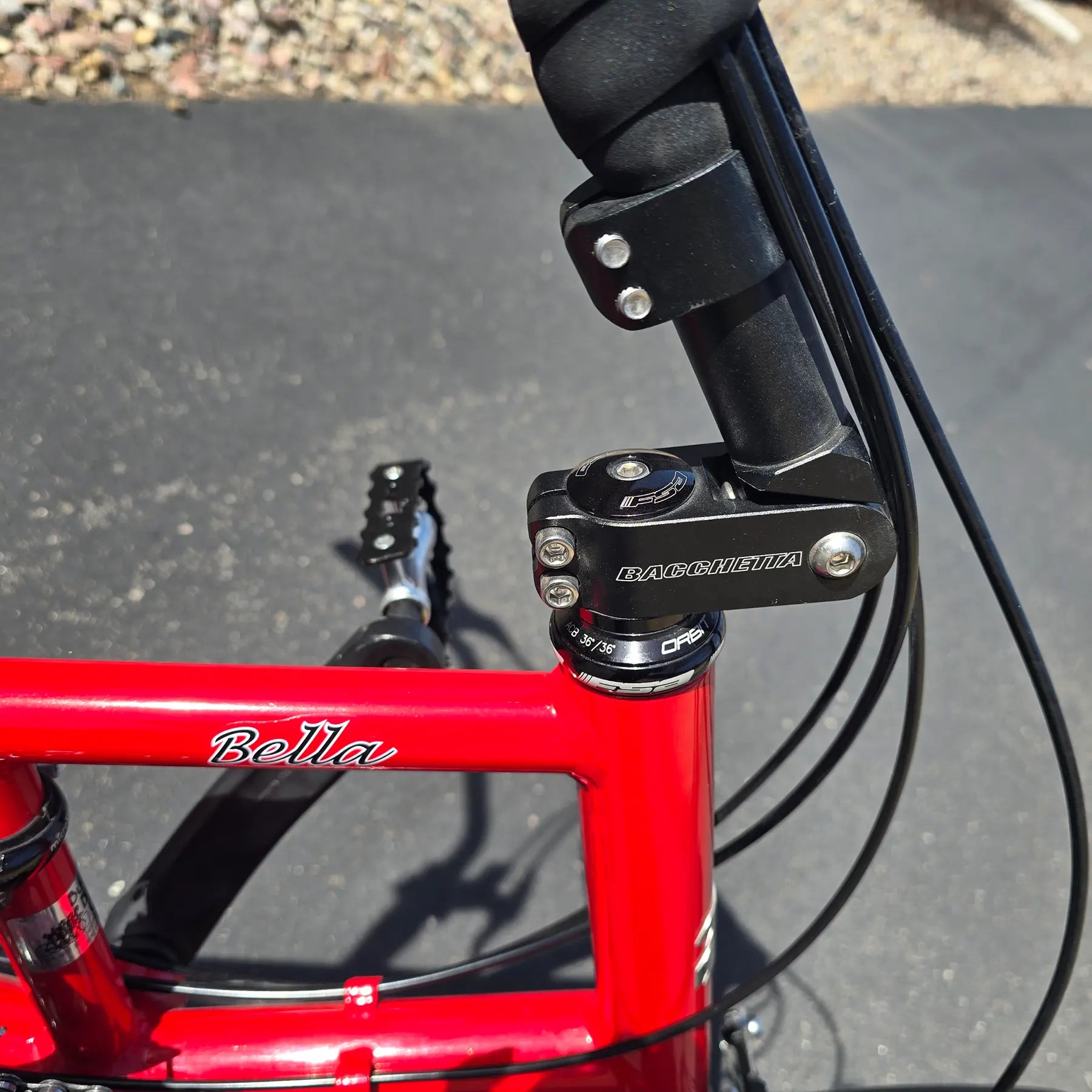 Closeup view of the handlebar adjustment pivot on the Bacchetta Used Bella Red SM-MD Recumbent Bike in an outdoor setting.