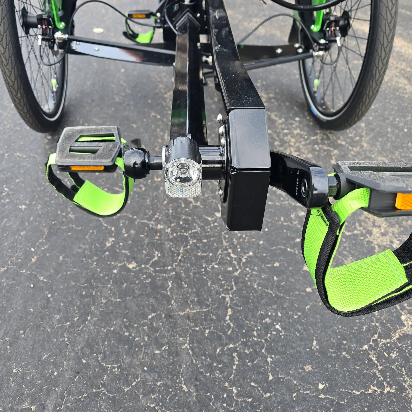 Closeup front view of the headlight and pedals on the BamBuk Independent Bosch Performance CX Recumbent Tandem Trike in the Hostel Shoppe parking lot.