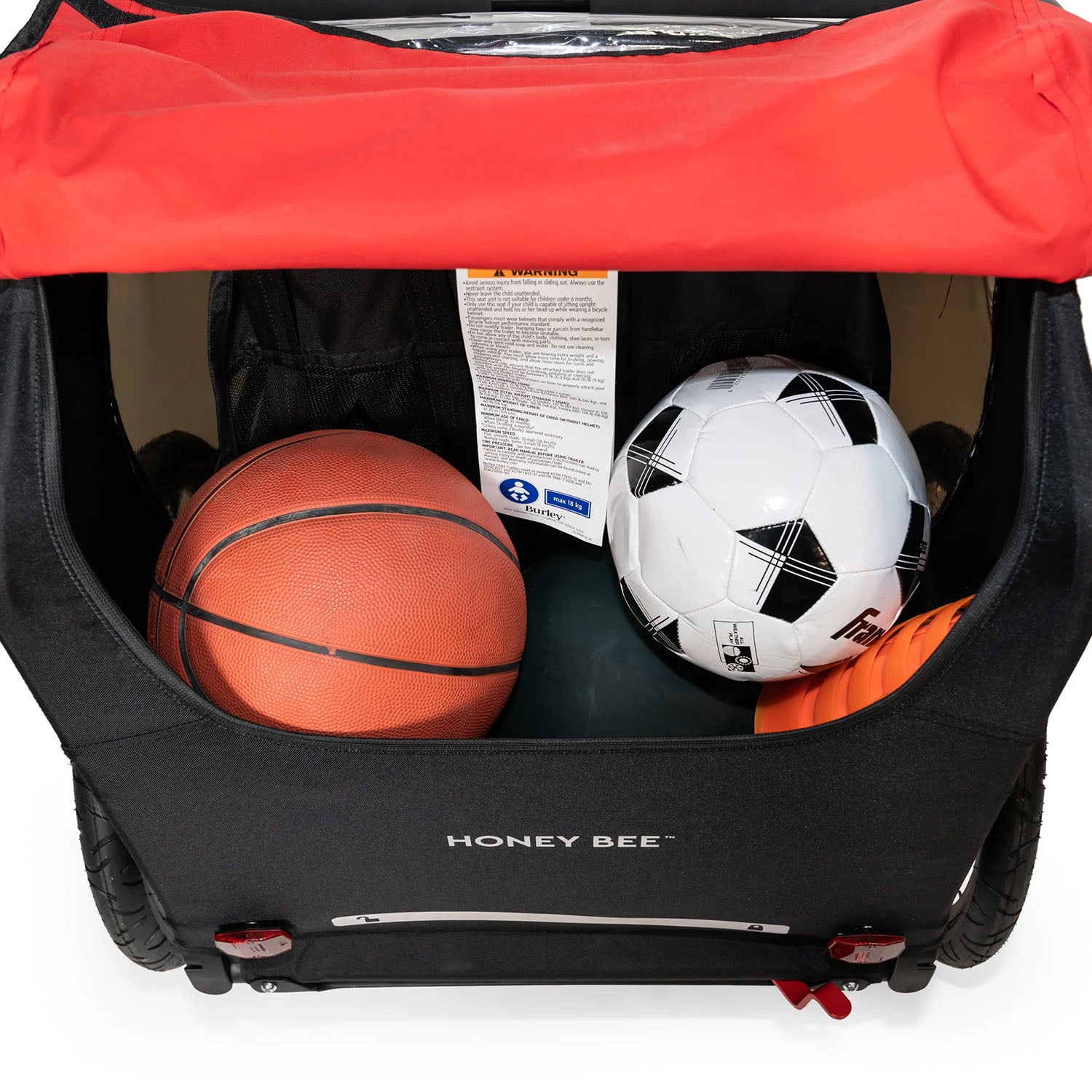 Rear detail view of the Burley Honey Bee Double Child Trailer in Red, showing sporting goods items in the rear storage space, on a white background.