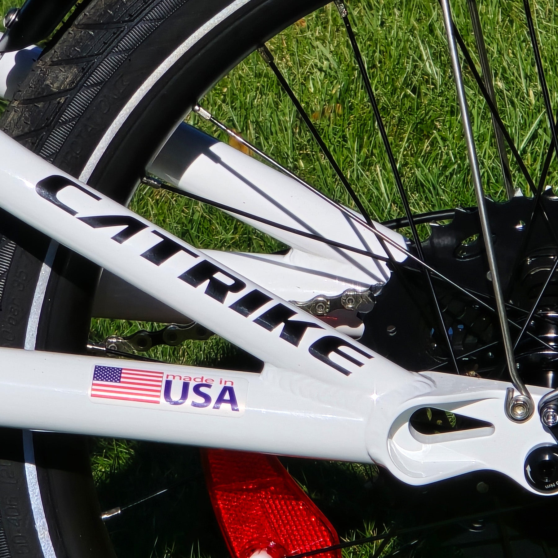 Close-up of a trike frame with 'Catrike' branding and an American flag sticker on grass.