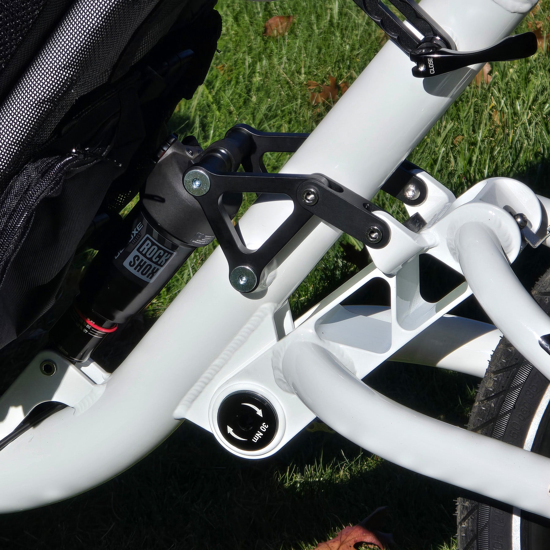 Close-up of a trike suspension rear shock with brand name "Rockshox" on grass.