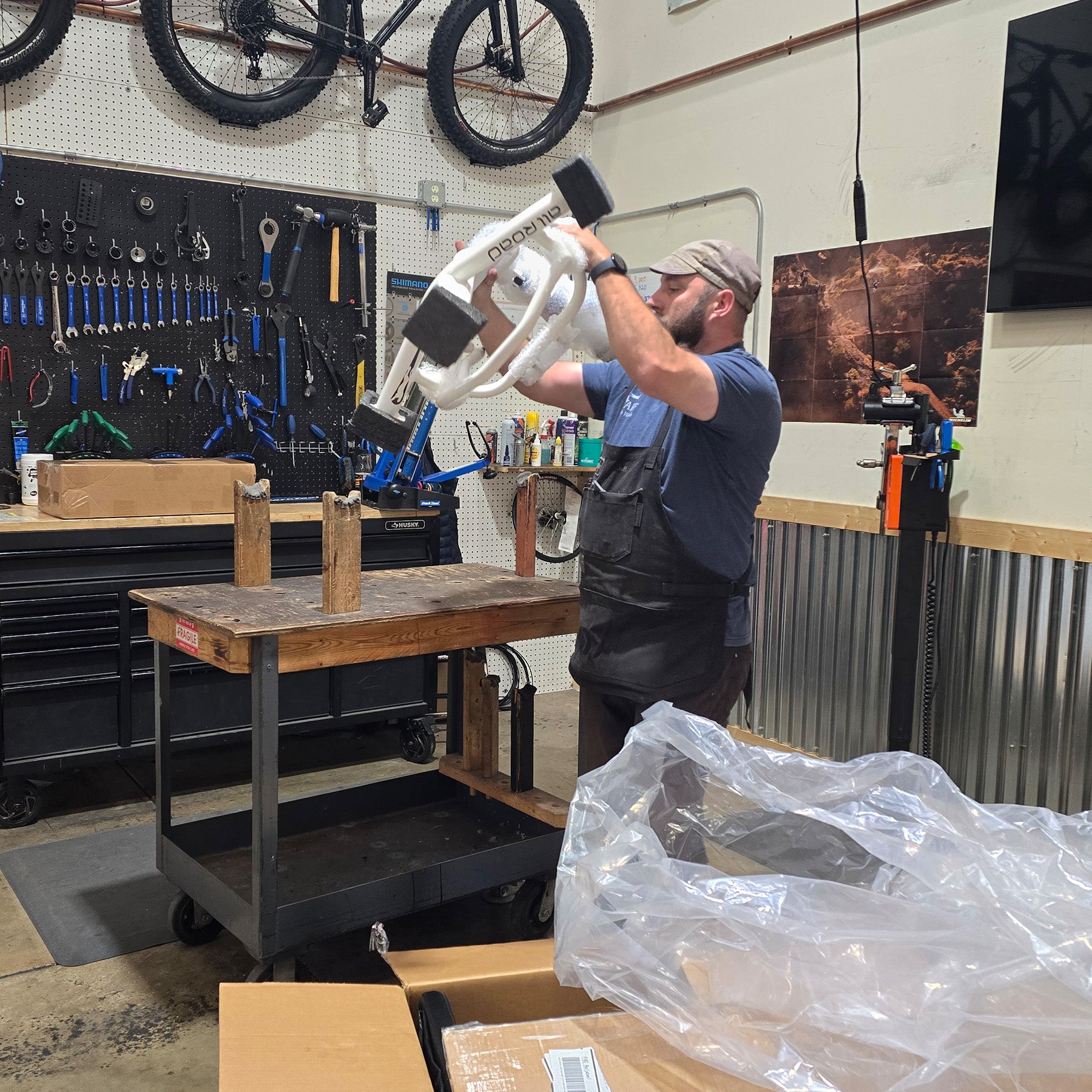 Person working on a tricycle in a workshop with tools and equipment around.