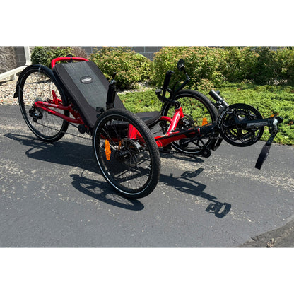 Angled view of a Demo Catrike Dumont in Lava Red in an outdoor setting.