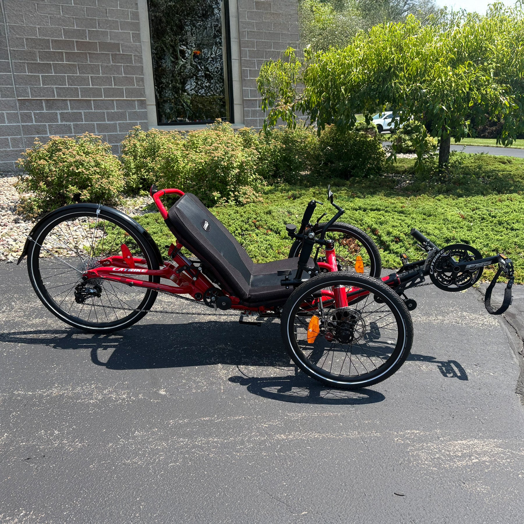 Side view of a Demo Catrike Dumont in Lava Red in an outdoor setting.