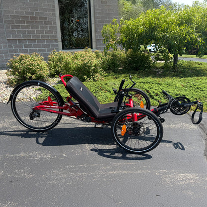 Side view of a Demo Catrike Dumont in Lava Red in an outdoor setting.