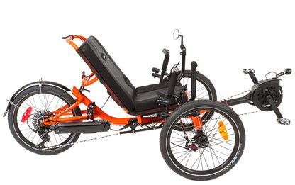 Studio image of orange recumbent trike with black motor, seat, tires, handlebars, and battery.