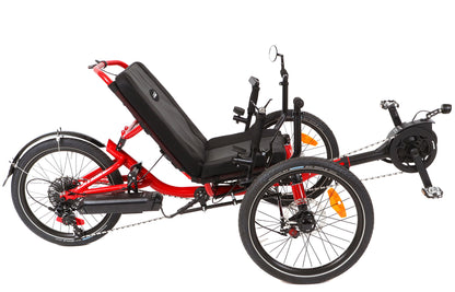 Studio image of side profile view of a red recumbent trike with black motor, seat, tires, handlebars, and battery.