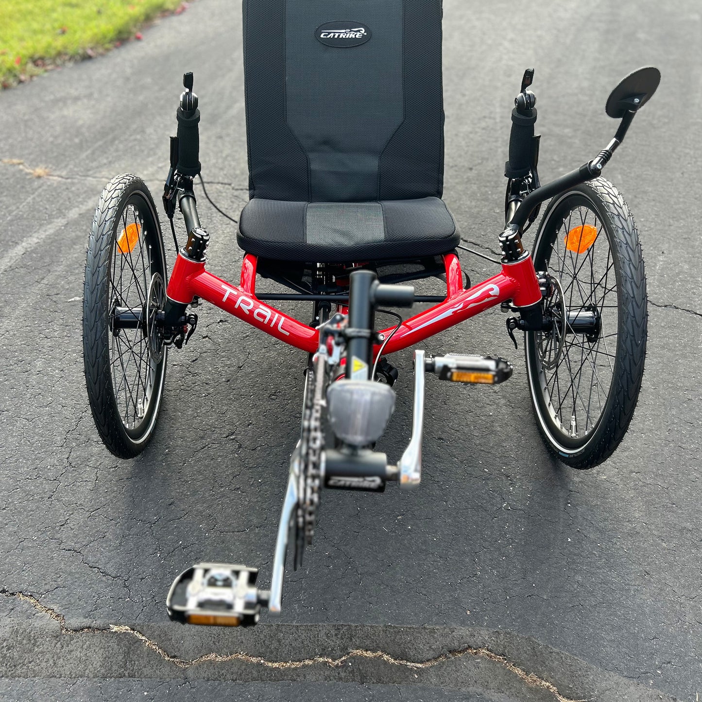 Front view of a Catrike Trail Compact Recumbent Trike in Lava Red in an outdoor setting.