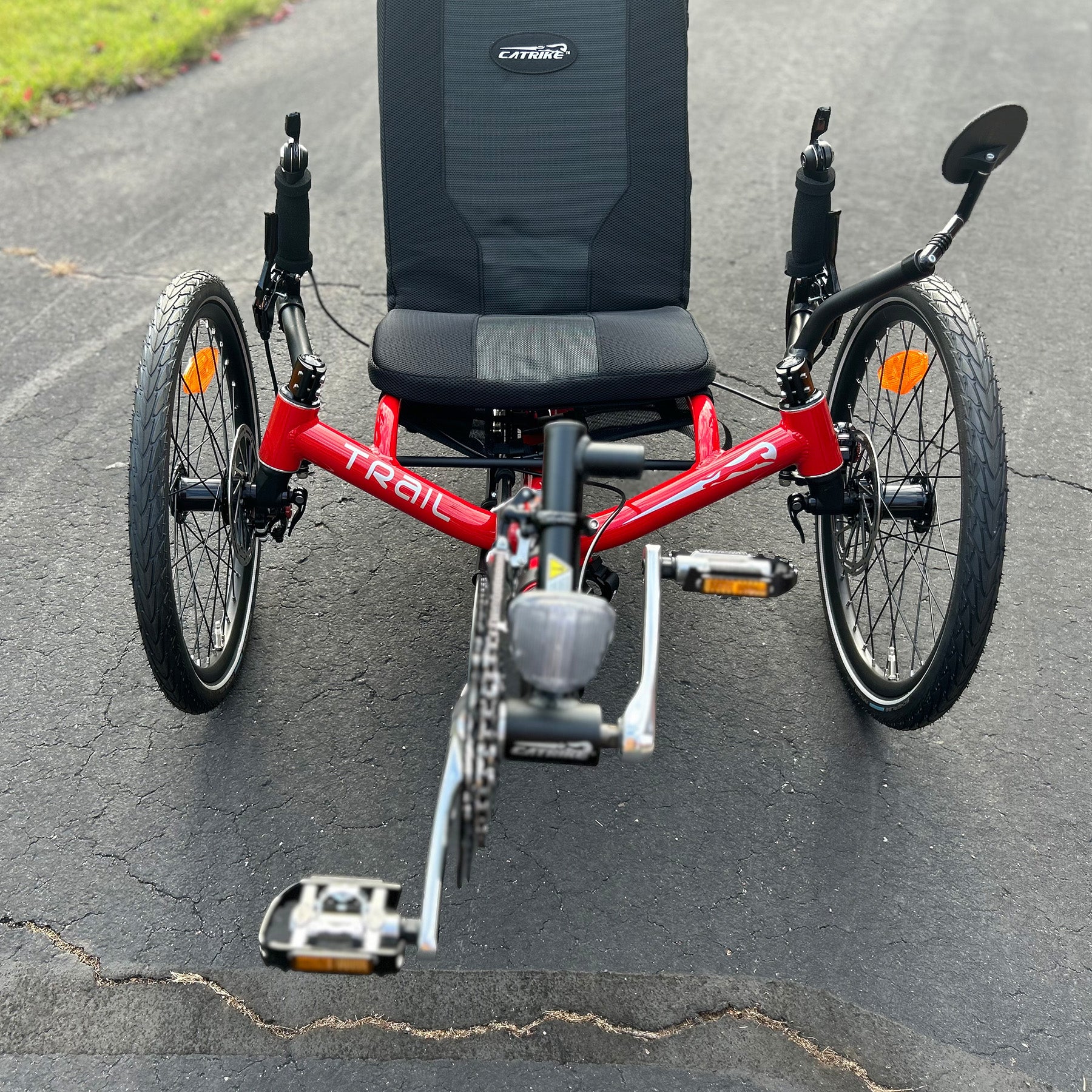 Front view of a Catrike Trail Compact Recumbent Trike in Lava Red in an outdoor setting.