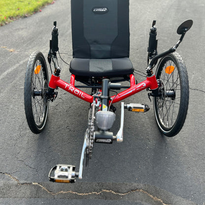 Front view of a Catrike Trail Compact Recumbent Trike in Lava Red in an outdoor setting.