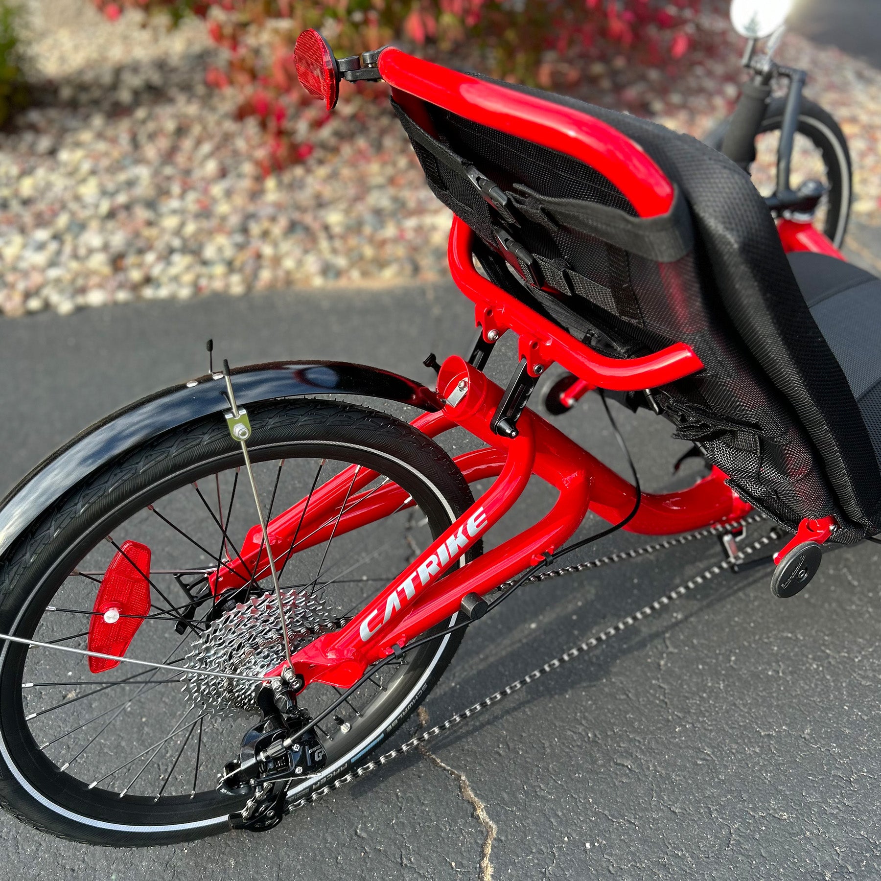 Closeup back view of a Catrike Trail Compact Recumbent Trike in Lava Red in an outdoor setting.
