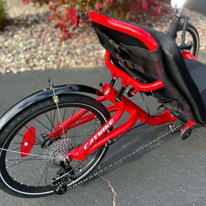 Closeup back view of a Catrike Trail Compact Recumbent Trike in Lava Red in an outdoor setting.