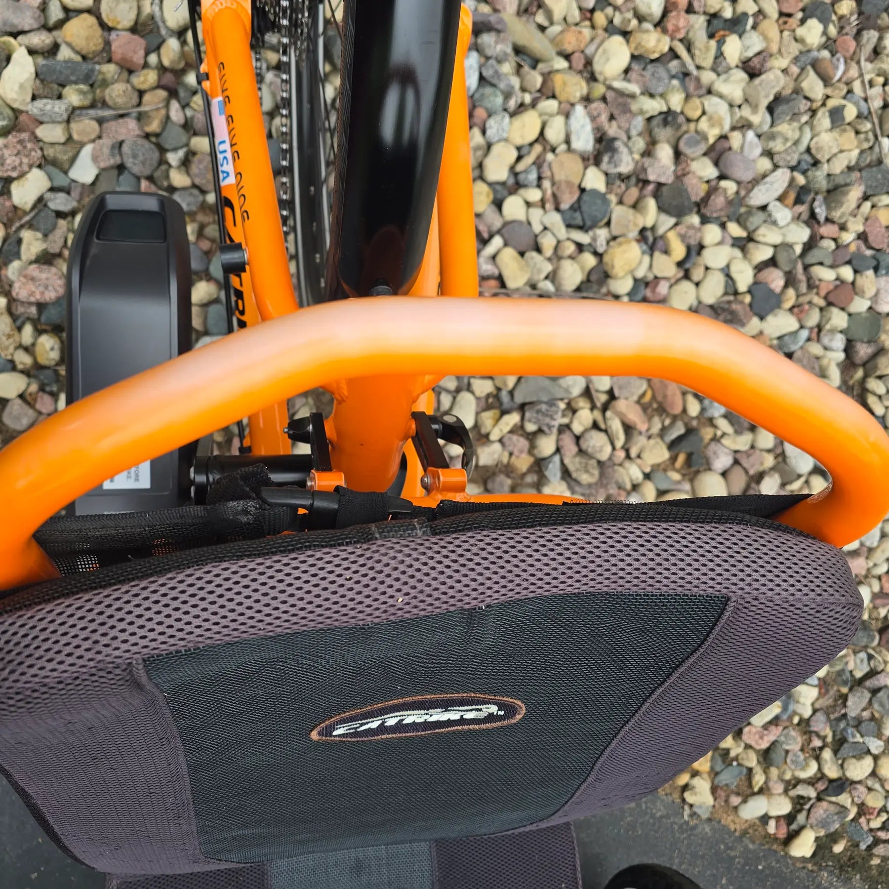 Closeup view of the seat frame showing sun fading on the Catrike Used 5.5.9. e-Cat Atomic Orange Recumbent Trike in an outdoor setting.