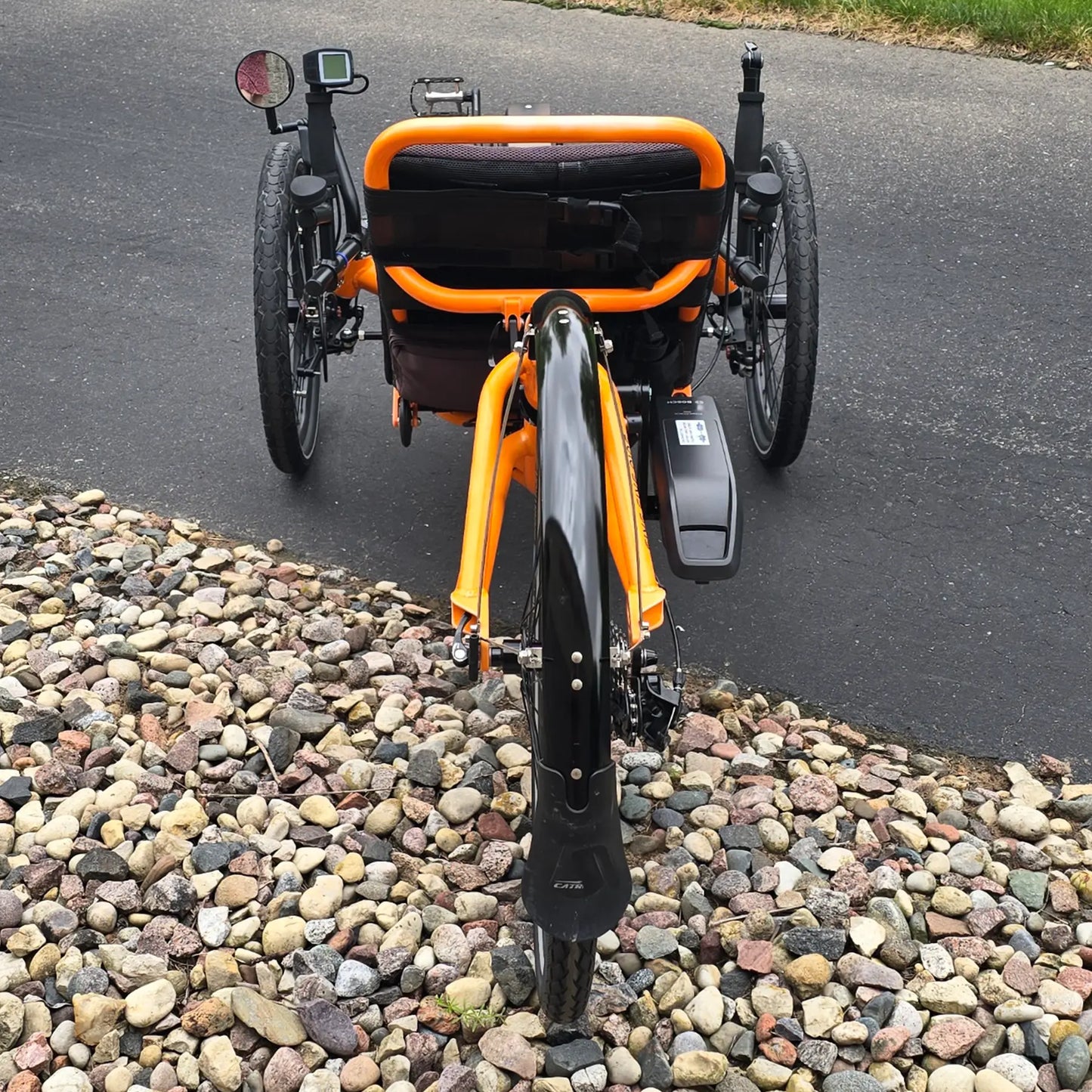 Rear view of the Catrike Used 5.5.9. e-Cat Atomic Orange Recumbent Trike in an outdoor setting.