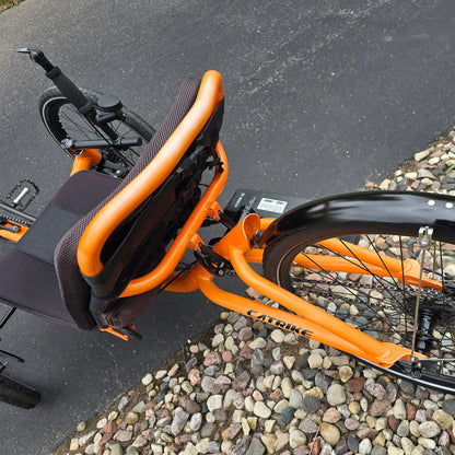 Closeup view of the Catrike Used 5.5.9. e-Cat Atomic Orange Recumbent Trike in an outdoor setting.