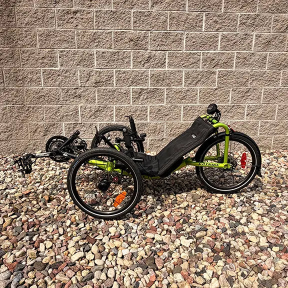 Non-drive side view of the Catrike Used Pocket Eon Green Recumbent Trike in an outdoor setting.