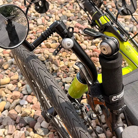 Closeup view of the right mirror, bell and shifter on the Catrike Used Pocket Eon Green Recumbent Trike in an outdoor setting.