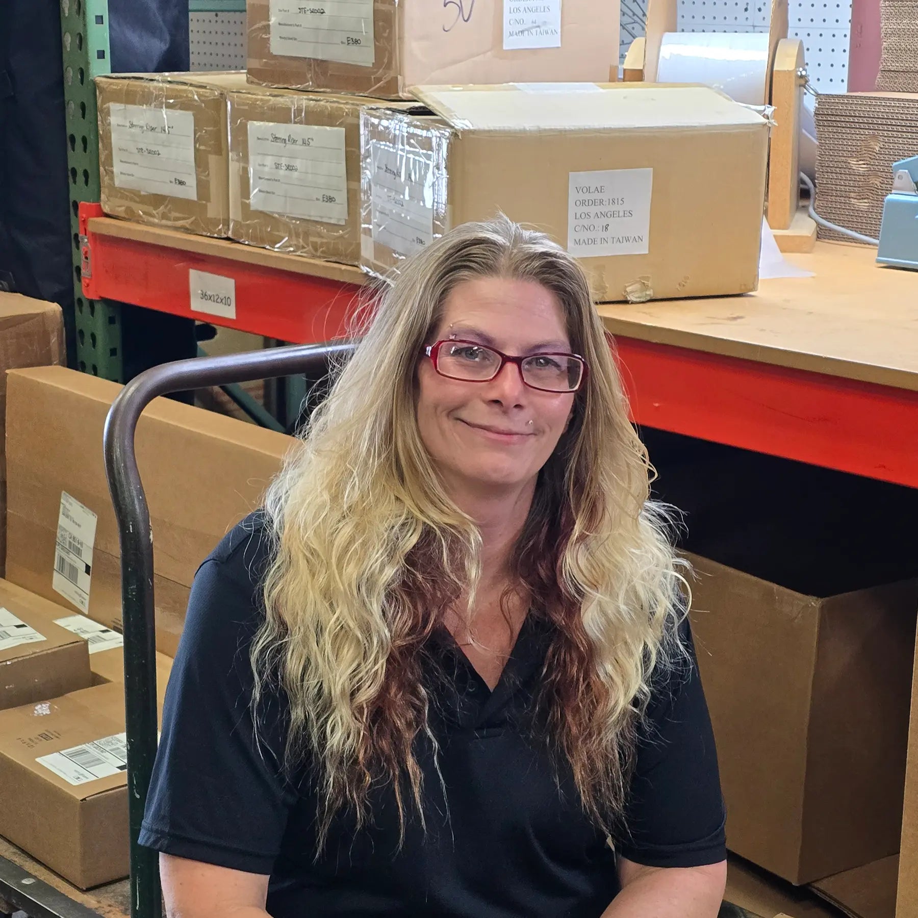 Chanda, our Shipping and Receaving Inventory Specialist in the shipping department in front of boxes ready to ship.