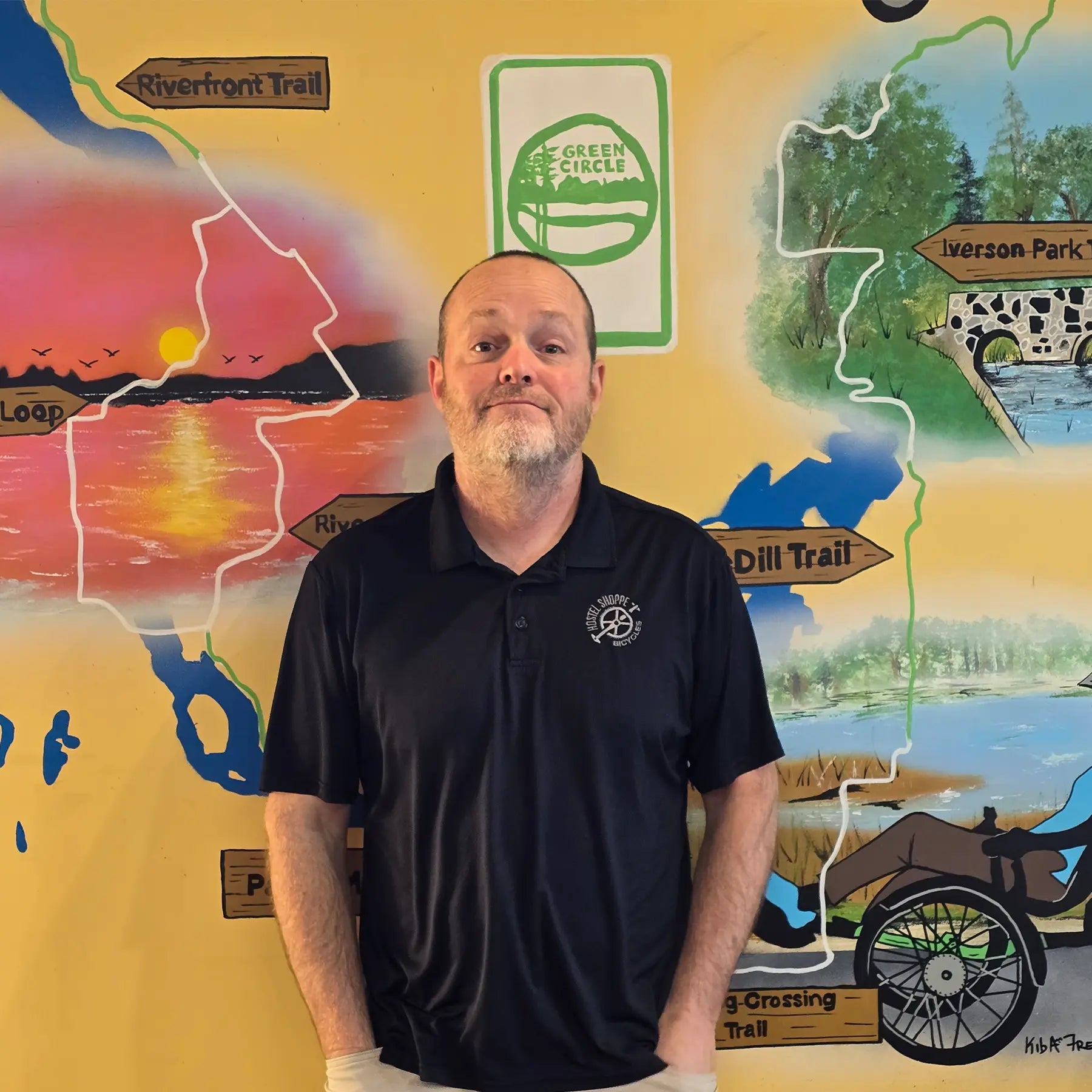 Chris, Sales Manager, in front of the Shoppe's Green Circle Mural, painted by KIBA Freeman Art: Muralist.