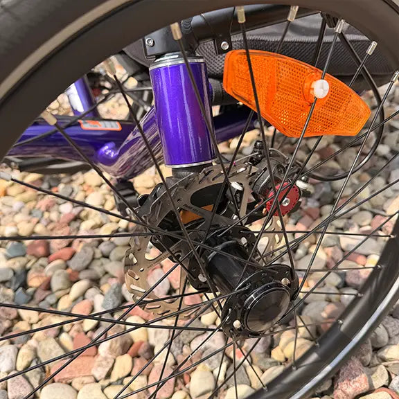 Closeup view of the front wheel on the Catrike Demo Dumont Compact Candy Purple Recumbent Trike in an outdoor setting.