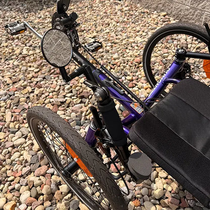 Closeup view of the mirror and left shifter on the Catrike Demo Dumont Compact Candy Purple Recumbent Trike in an outdoor setting.