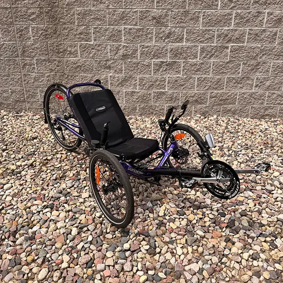 Angled side view of the Catrike Demo Dumont Compact Candy Purple Recumbent Trike in an outdoor setting.