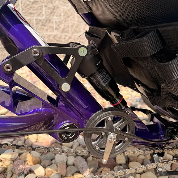 Side view of the rear suspension on the Catrike Demo Dumont Compact Candy Purple Recumbent Trike in an outdoor setting.